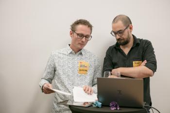 Zwei GLOBAL 2000 Mitarbeiter stehen vor einem Laptop und tauschen sich über etwas aus