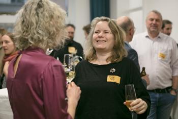 Zwei Frauen reden miteinander und lachen. Sie haben jeweils ein Glas Sekt in der Hand.