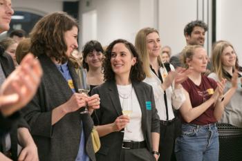 Man sieht das Publikum wie es klatscht und lächelt.