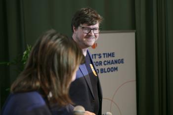 Nikolai Miron im blauen Sakko steht auf der Bühne und lächelt Eva Gänsdorfer zu