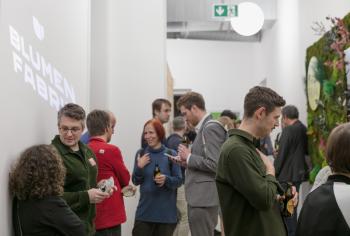 Im Empfangsbereich der Blumenfabrik stehen Besucher:innen und unterhalten sich.