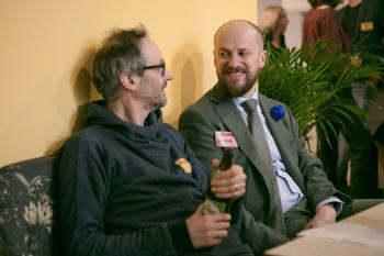 Zwei Männer sitzen auf einem Sofa und reden miteinander