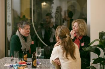 drei Frauen sitzen an einem Tisch und reden miteinander. 