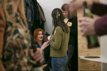 Drei Frauen bei der Garderobe reden miteinander.