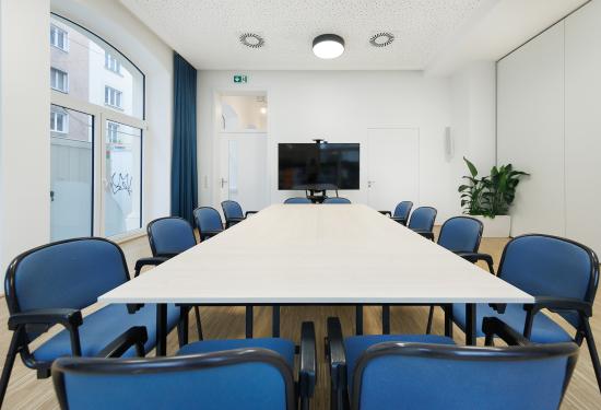 Meetingraum mit Tisch, Bildschrim und Sessel