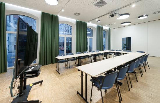 Meetingraum mit Tisch, Stühlen und Bildschirm